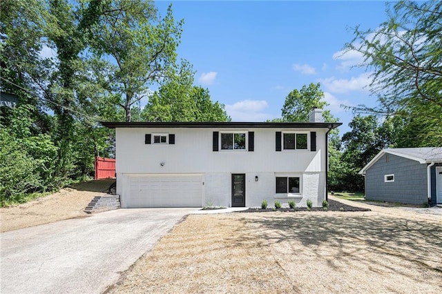 view of front facade with driveway, a chimney, and a garage