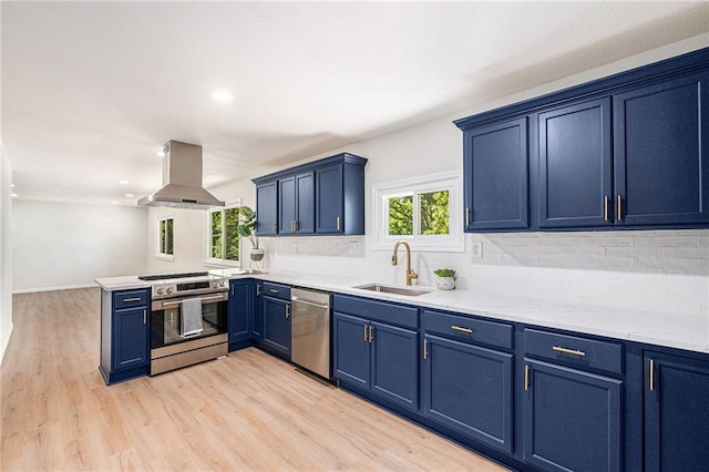 kitchen featuring appliances with stainless steel finishes, a sink, blue cabinetry, backsplash, and island range hood