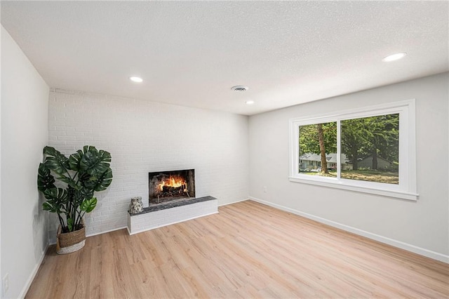 unfurnished living room featuring light wood finished floors, a fireplace, baseboards, and recessed lighting