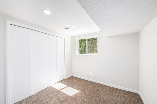 unfurnished bedroom featuring carpet floors, recessed lighting, a closet, baseboards, and a textured ceiling