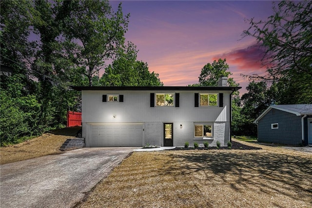 view of front of home featuring concrete driveway, an attached garage, and a chimney