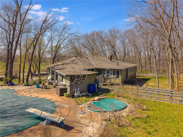rear view of house with a fenced in pool, stucco siding, a chimney, a patio area, and fence