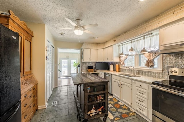kitchen featuring ceiling fan, white cabinetry, a sink, stainless steel appliances, and backsplash