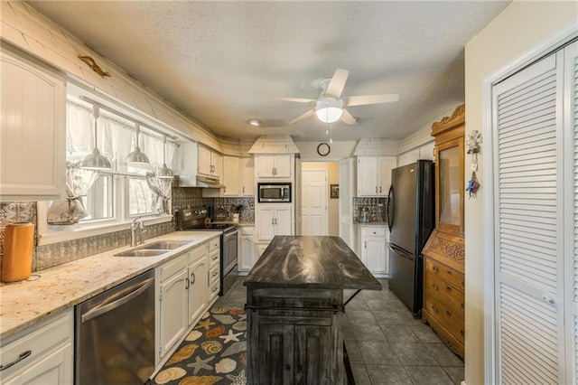 kitchen with a textured ceiling, white cabinets, decorative backsplash, stainless steel appliances, and a sink