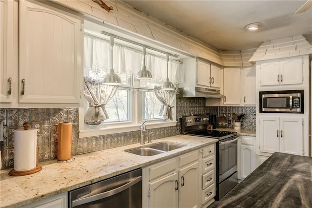 kitchen featuring white cabinets, a sink, under cabinet range hood, stainless steel appliances, and decorative backsplash