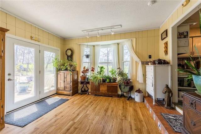 entryway featuring light wood-style floors, a textured ceiling, ornamental molding, and track lighting