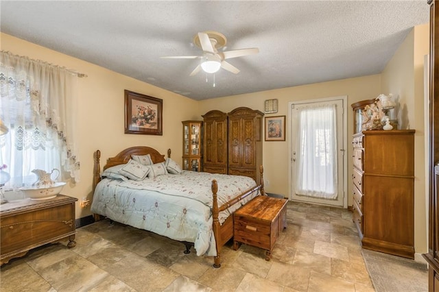 bedroom featuring a textured ceiling, stone finish floor, a ceiling fan, and access to exterior