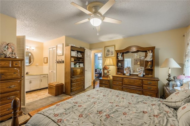 bedroom with ceiling fan, connected bathroom, and a textured ceiling