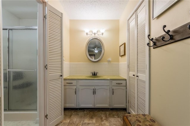 bathroom with vanity, a closet, a textured ceiling, and a stall shower