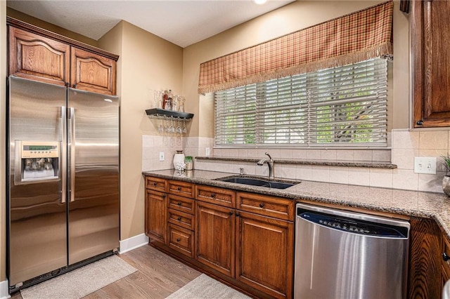 kitchen with a sink, tasteful backsplash, stainless steel appliances, and light wood finished floors
