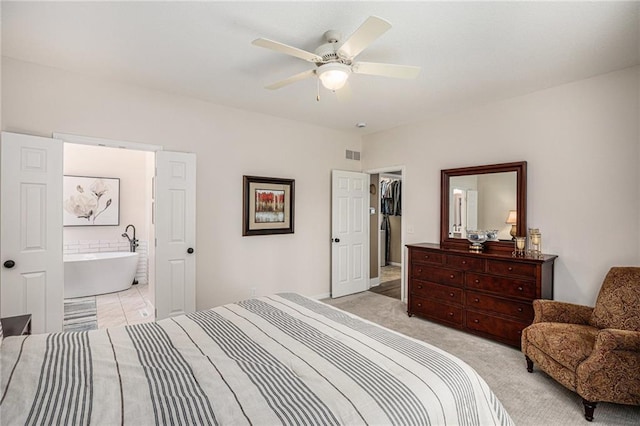 bedroom featuring a ceiling fan, visible vents, light carpet, and ensuite bath