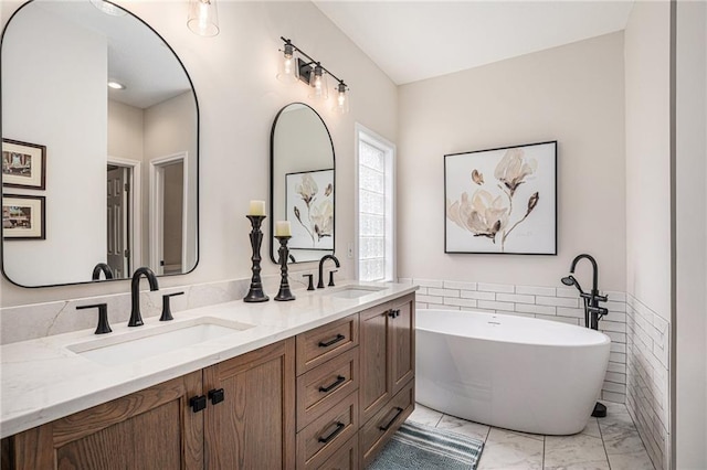 bathroom featuring double vanity, a sink, marble finish floor, and a freestanding bath