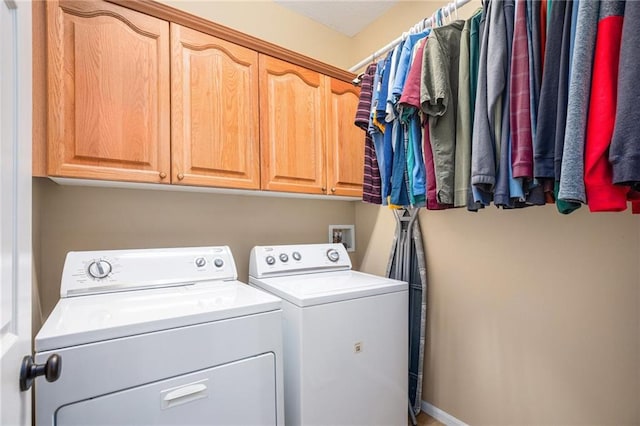 clothes washing area featuring independent washer and dryer, baseboards, and cabinet space