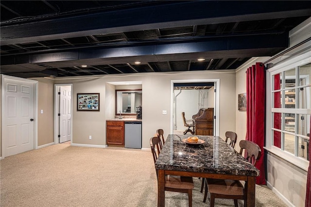 dining room featuring indoor bar, baseboards, and light carpet