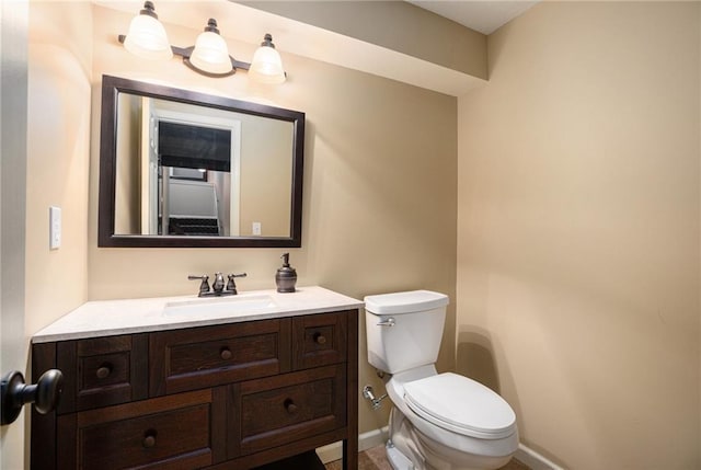 half bath with toilet, baseboards, and vanity