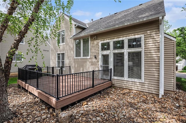 rear view of property featuring a deck and roof with shingles