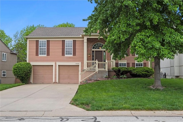 raised ranch with a garage, concrete driveway, and a front lawn