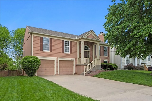 raised ranch with fence, an attached garage, concrete driveway, and a front yard