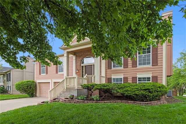 split foyer home featuring an attached garage, driveway, central AC, and a front yard