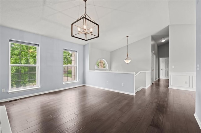 unfurnished room featuring an inviting chandelier, lofted ceiling, visible vents, and dark wood-type flooring