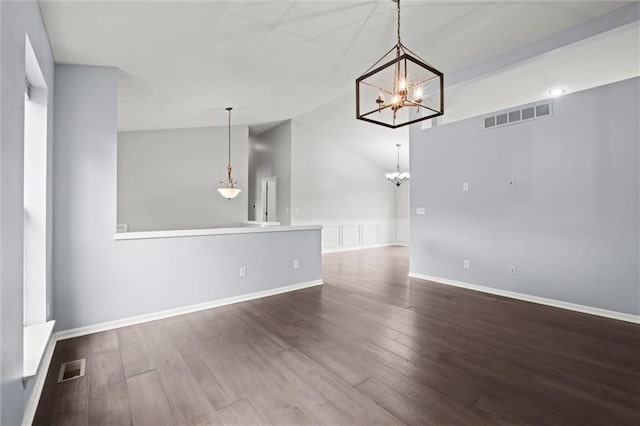 unfurnished dining area featuring vaulted ceiling, a notable chandelier, dark wood finished floors, and visible vents