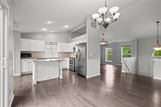 kitchen featuring vaulted ceiling, a sink, white cabinets, an inviting chandelier, and stainless steel appliances