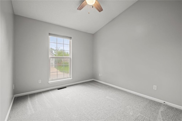 carpeted spare room featuring baseboards, ceiling fan, vaulted ceiling, and visible vents