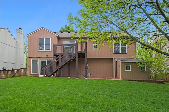 rear view of property with stairs, an attached garage, a wooden deck, a fenced backyard, and a yard