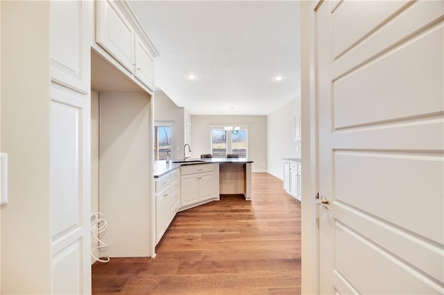 9435 N Belton Ave, Kansas City, MO 64154 - kitchen with a sink, light wood-style floors, a peninsula, recessed lighting, and white cabinetry
