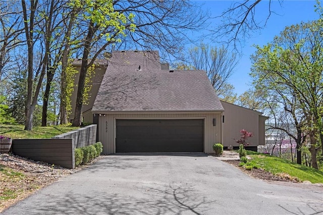 view of side of property featuring a garage and a shingled roof