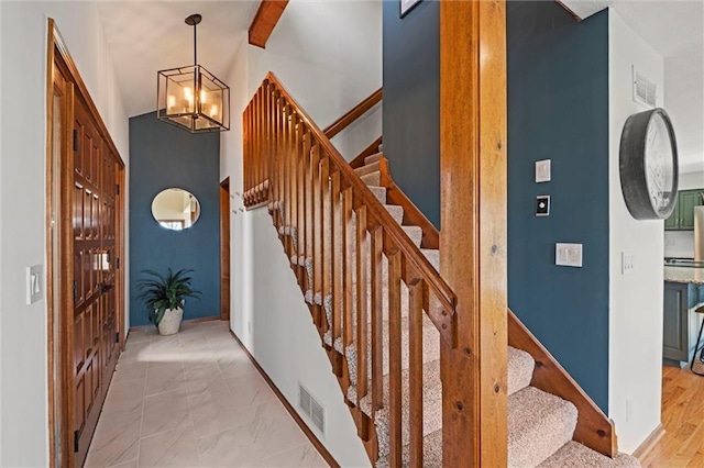 entryway with visible vents, lofted ceiling, stairs, and a notable chandelier