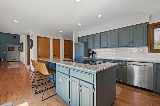 kitchen with a kitchen island, stainless steel dishwasher, backsplash, and light wood-style flooring