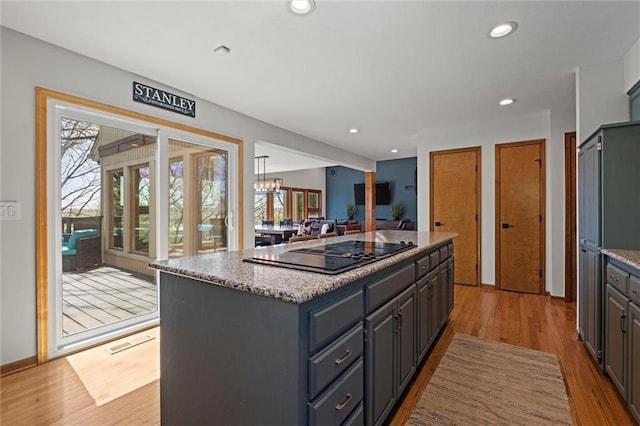 kitchen featuring a kitchen island, black electric cooktop, recessed lighting, and light wood finished floors