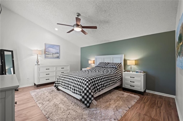 bedroom with baseboards, a textured ceiling, wood finished floors, and vaulted ceiling