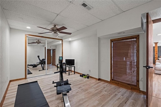 exercise area with ceiling fan, a paneled ceiling, visible vents, wood finished floors, and baseboards
