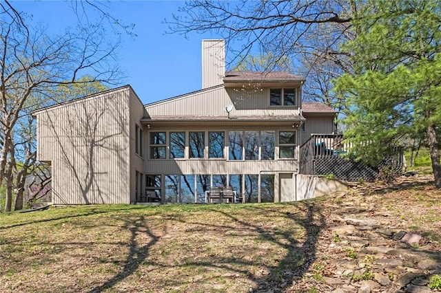 rear view of house featuring a deck, a chimney, and a sunroom