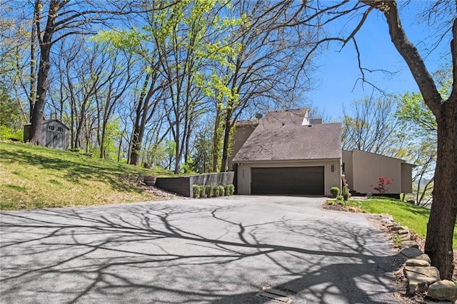 view of property exterior featuring a garage, aphalt driveway, and a yard
