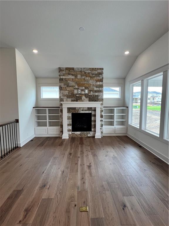 16372 Spring Valley St, Gardner, KS 66030 - unfurnished living room featuring wood finished floors, lofted ceiling, a stone fireplace, baseboards, and recessed lighting