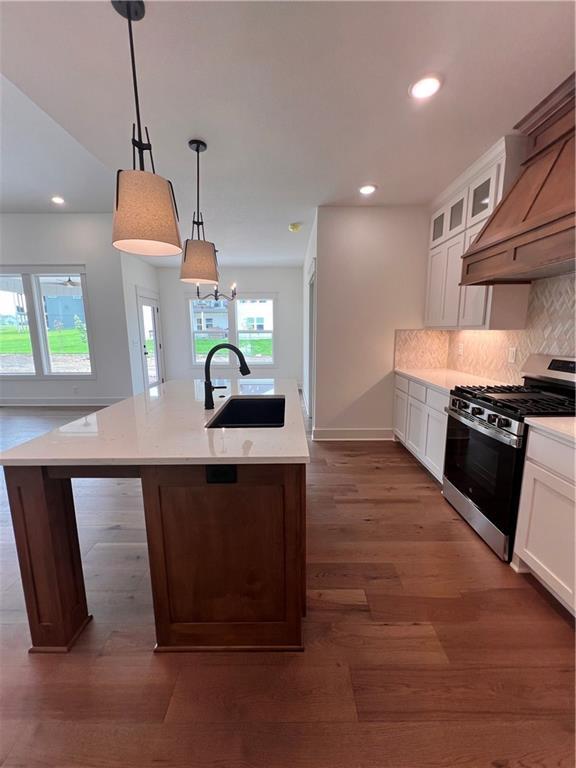 16372 Spring Valley St, Gardner, KS 66030 - kitchen with gas stove, a sink, a kitchen island with sink, backsplash, and light countertops