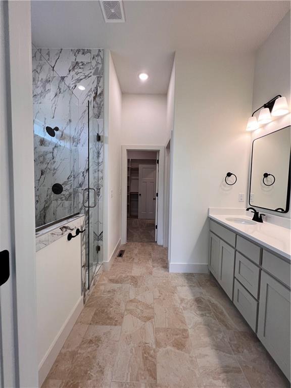 16372 Spring Valley St, Gardner, KS 66030 - bathroom featuring vanity, a marble finish shower, baseboards, a walk in closet, and stone finish flooring