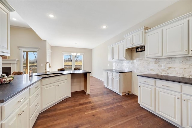9331 N Belton Ave, Kansas City, MO 64154 - kitchen featuring a sink, dark countertops, decorative backsplash, and dark wood-type flooring