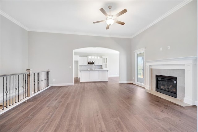 9335 N Belton Ave, Kansas City, MO 64154 - unfurnished living room featuring crown molding, wood finished floors, baseboards, ceiling fan, and arched walkways