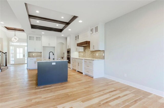 3217 SW Saddlebred Ter, Lees Summit, MO 64082 - kitchen with recessed lighting, tasteful backsplash, light wood-type flooring, white cabinetry, and a center island with sink