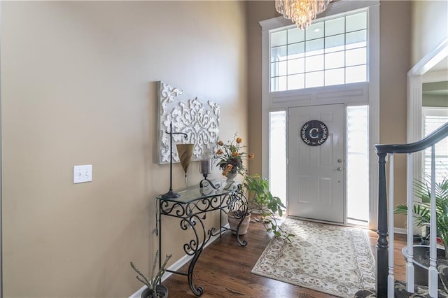 foyer featuring wood finished floors, an inviting chandelier, a high ceiling, and a healthy amount of sunlight