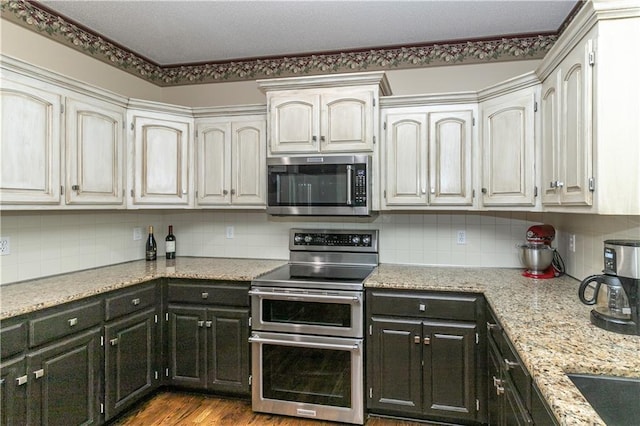 kitchen with tasteful backsplash, appliances with stainless steel finishes, and dark cabinetry