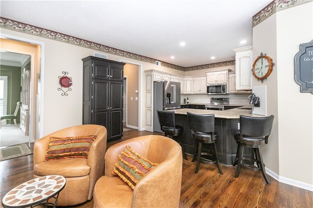 kitchen featuring stainless steel appliances, dark wood-type flooring, a peninsula, and a breakfast bar