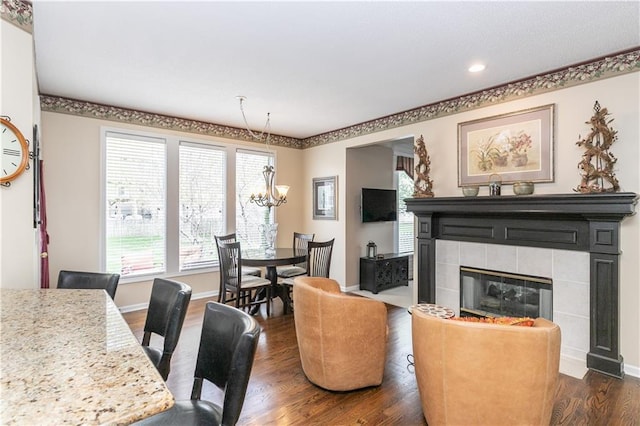 living area featuring a fireplace, dark wood-type flooring, recessed lighting, a notable chandelier, and baseboards