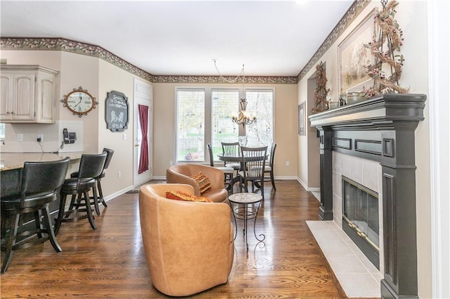living room featuring a fireplace with flush hearth, wood finished floors, baseboards, and a notable chandelier