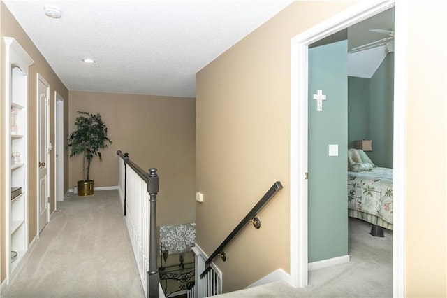 corridor featuring light colored carpet, baseboards, and an upstairs landing