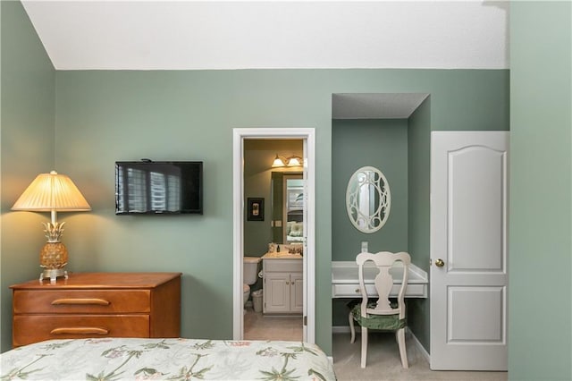 carpeted bedroom with ensuite bath and baseboards